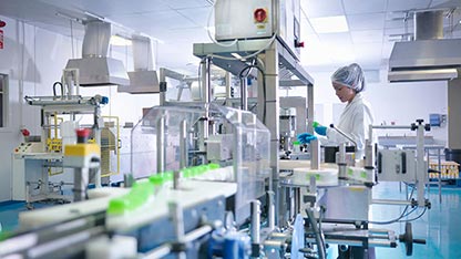 Ouvrier inspectant des produits sur la chaîne de production d'une usine pharmaceutique