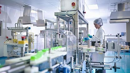 Arbeiter, der Produkte an der Produktionslinie in einer pharmazeutischen Fabrik inspiziert